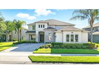 Elegant two-story home boasts a stone facade, manicured landscaping, and a paver driveway at 13924 Jomatt Loop, Winter Garden, FL 34787