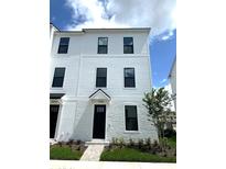 Charming three-story townhome features a brick facade, manicured lawn, and black framed windows at 15125 Grove Lake Dr, Winter Garden, FL 34787