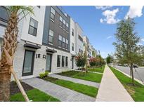 Modern townhouse exterior featuring brick accents, landscaping, and a sidewalk along the street at 2296 Brix Sts, Orlando, FL 32804