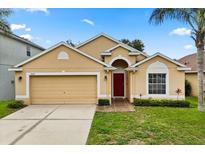 Inviting single-story home with a well-manicured lawn, attached garage, and a vibrant red front door at 2422 Holly Pine Cir, Orlando, FL 32820