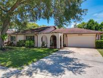 Charming single-story home featuring a spacious driveway, manicured lawn, and unique architectural details at 8346 Mattituck Cir, Orlando, FL 32829