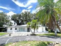 Charming single-story home with white exterior, mature trees, and ample parking space at 9148 Oakwood Dr, Lake Wales, FL 33898