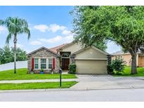 Charming one-story home with stone accents, manicured lawn, mature trees, and two-car garage at 1112 Spruce Ridge Ct, Minneola, FL 34715