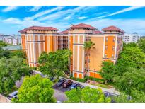 Beautiful resort condo building with lush trees and a colorful exterior paint job at 12527 Floridays Resort Dr # E104, Orlando, FL 32821
