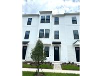 Beautiful three-story townhome featuring white siding, black trim, and well manicured landscaping at 15119 Grove Lake Dr, Winter Garden, FL 34787