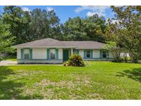 Charming single-story home featuring a well-maintained lawn, complemented by a green door and blue shutters at 19 Hemlock Terrace Way, Ocala, FL 34472