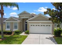 Charming home featuring a two-car garage, well-maintained lawn, and beautiful landscaping at 2222 Wyndham Palms Way, Kissimmee, FL 34747