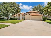 Charming two-story home featuring a three-car garage, well-manicured lawn, and inviting arched entryway at 2250 Blossomwood Dr, Oviedo, FL 32765