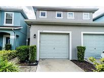 Two-car garage of townhome with grey exterior paint and well-manicured shrubbery at 2337 Bexley Pl, Casselberry, FL 32707
