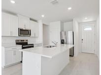 Bright kitchen features white cabinets, stainless steel appliances, and a large center island with sink at 2770 Virginia Pine Dr, Bartow, FL 33830