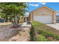 Tan single-story home featuring an attached garage, well-kept shrubs, and mature landscaping at 2838 Maldive Ct, Deltona, FL 32738