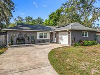 Charming single-story home with gray exterior, landscaped yard, and winding driveway under a sunny sky at 604 Thrush Ave, Longwood, FL 32750