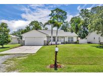 Charming single-story home with a well-manicured lawn, mature trees, and a two-car garage at 1181 Pine Ln, St Cloud, FL 34771