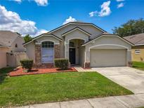 Charming single-Gathering home featuring a well-manicured lawn and an attached two-car garage at 12938 Maribou Cir, Orlando, FL 32828