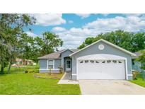 Charming single-story home featuring a well-maintained lawn, blue siding, and two-car garage at 339 Colony Ct, Kissimmee, FL 34758