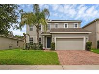 Charming two-story home featuring a well-manicured lawn and a brick-paved driveway leading to a two-car garage at 3472 Gretchen Dr, Ocoee, FL 34761