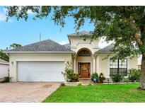 Charming single-Gathering home showcasing a well-manicured lawn, brick driveway, and attached two-car garage at 501 Lake Cummings Way, Lake Alfred, FL 33850