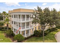 Three-story condo with multiple balconies, yellow and cream color scheme, and well-maintained landscaping at 7509 Mourning Dove Cir # 204, Reunion, FL 34747