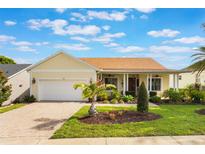 Charming single Gathering home with manicured lawn, brick driveway, and inviting covered porch at 930 Willow Oak Loop, Minneola, FL 34715