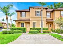 Inviting two-story townhome with a well-manicured lawn, mature palms, and a brick-paved driveway for easy parking at 109 Cambria Ave, Davenport, FL 33897
