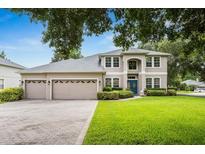 Charming two-story home boasts lush landscaping, a three-car garage, and a welcoming blue front door at 127 Heatherbrooke Cir, Oviedo, FL 32765