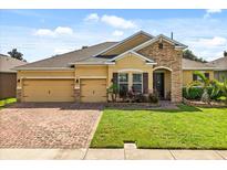 Charming single-story home featuring a brick driveway, manicured lawn, and a stone-accented entrance at 1507 Alligator St, St Cloud, FL 34771