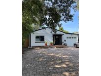 Charming one-story home featuring a brick driveway, white paint, black trim, and a well-manicured lawn at 162 Orange Pl, Maitland, FL 32751
