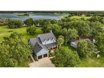 Aerial view of a charming blue two-story home with a two-car garage and front porch near a lake at 16610 County Line Rd, Umatilla, FL 32784