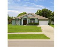 Beautiful one-story home with a manicured lawn, mature trees, and an attached two-car garage at 1784 Providence Blvd, Deltona, FL 32725