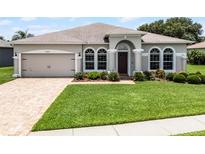 Charming home with a manicured lawn, brick driveway, and arched windows with decorative trim at 2085 Stone Cross Cir, Orlando, FL 32828