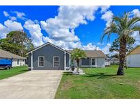 Charming single-story home with a well-manicured lawn, palm trees, and gray and white exterior paint at 2936 Estill St, Deltona, FL 32738