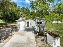 Exterior view of home with a concrete drive, small shed and mature tree in a landscaped yard at 4925 Catfish Rd, Lake Wales, FL 33898