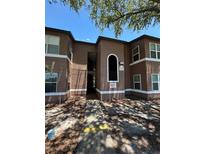 Two-story brown and white apartment building with a sidewalk leading to an entrance and trees overhead at 5725 Gatlin Ave # 315, Orlando, FL 32822