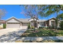 Charming single-story home showcasing a well-manicured lawn, stone accents, and a three-car garage at 13157 Paloma Dr, Orlando, FL 32837