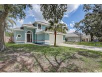 Charming two-story home featuring an attached two-car garage and mature trees in a manicured front yard at 10599 Satinwood Cir, Orlando, FL 32825