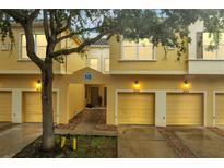 Inviting yellow townhome with individual garages, a walkway to front door and mature landscaping at 2820 Oakwater Dr # 2820, Kissimmee, FL 34747
