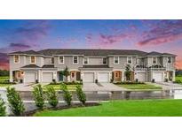 Modern townhome exteriors with individual garages and manicured lawns on a sunny day at 3603 Davenport Creek Ct, Kissimmee, FL 34746