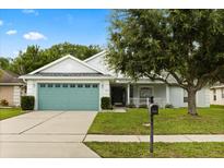 Charming single-story home featuring a teal garage door, well-manicured lawn, and mature landscaping at 3610 Doe Run Dr, St Cloud, FL 34772