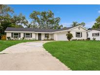 Charming single-story home featuring a spacious front yard, and a long curved driveway at 5021 Saint Marie Ave, Belle Isle, FL 32812