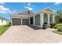 Charming single-story home boasting a brick driveway, a two-car garage, and a welcoming column-lined front porch at 5627 Orange Orchard Dr, Winter Garden, FL 34787