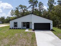 Charming single-story home featuring a modern design with a black door and a two-car garage at 6516 Sw 149 Th Lane Rd, Ocala, FL 34473