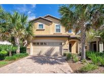 Inviting two-story home featuring a brick driveway, a two-car garage and tropical landscaping at 8901 Rhodes St, Kissimmee, FL 34747