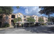 Condo exterior featuring covered parking, balconies, and mature trees at 13584 Turtle Marsh Loop # 12, Orlando, FL 32837
