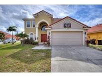 Charming two-story home featuring a red tile roof, arched entryway, and well-maintained landscaping at 148 Miro Dr, Davenport, FL 33837
