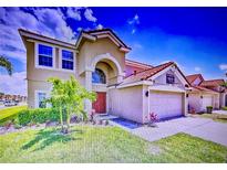 Two-story home with a red tile roof, red front door, and a well-manicured lawn at 148 Miro Dr, Davenport, FL 33837