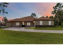 Inviting single-story home with a large front yard and a driveway, set against a beautiful sunset backdrop at 19606 Reynolds Pkwy, Orlando, FL 32833