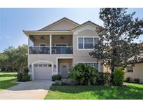 Two-story home showcasing a balcony, manicured lawn, and attached one-car garage at 20130 Sunset Landing Ave, Groveland, FL 34736