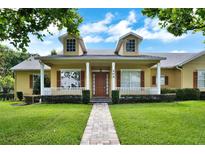 Charming home featuring a well-manicured lawn, covered front porch, and brick walkway leading to the entrance at 205 Trail Bridge Ct, Winter Garden, FL 34787