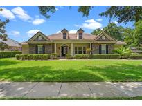 Charming stone home featuring a tile roof, manicured lawn, and lush landscaping at 25554 Hawks Run Ln, Sorrento, FL 32776