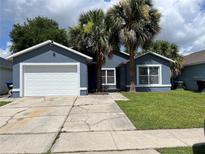 Charming single-story home featuring a well-maintained lawn, two palm trees, and a quaint blue exterior at 2833 Woodruff Dr, Orlando, FL 32837